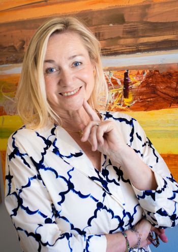 Eine Frau vor einem abstrakten Gemälde in warmen Farbtönen